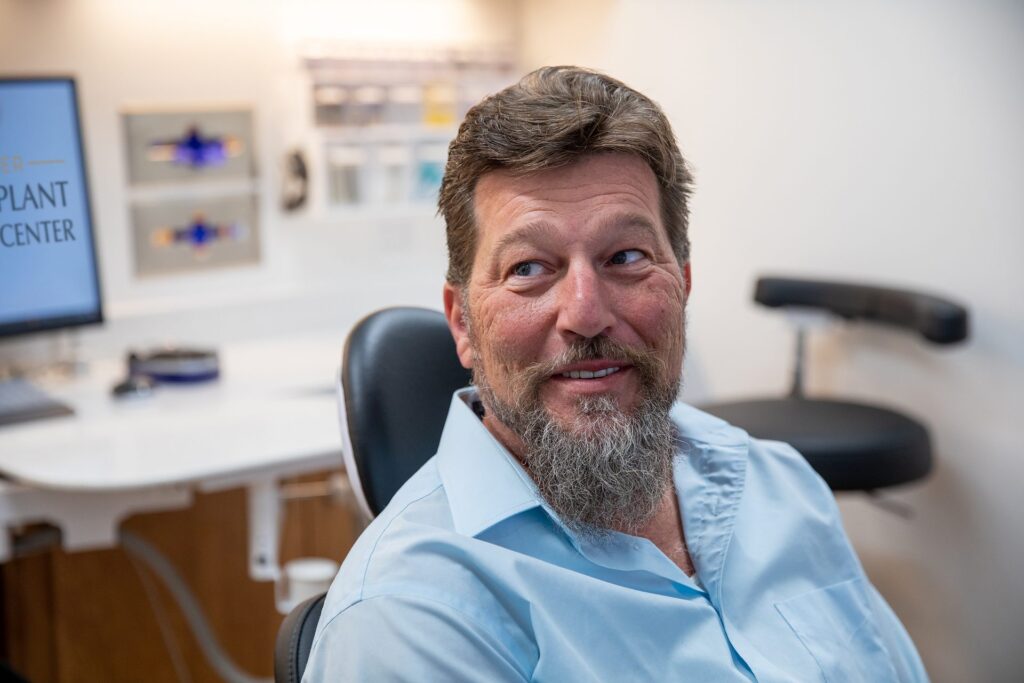 Smiling upper All-on-4 dental implant patient seated in the dental chair