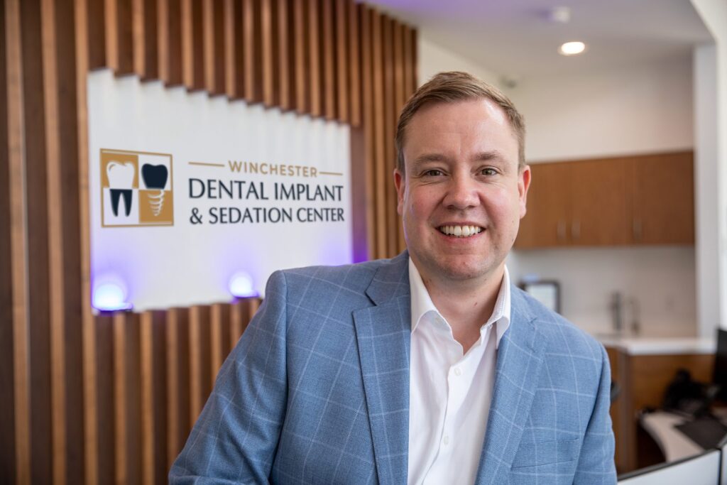 Dr. Niels Oestervemb, board-certified implant dentist, in front of the Winchester Dental Implant & Sedation Center sign
