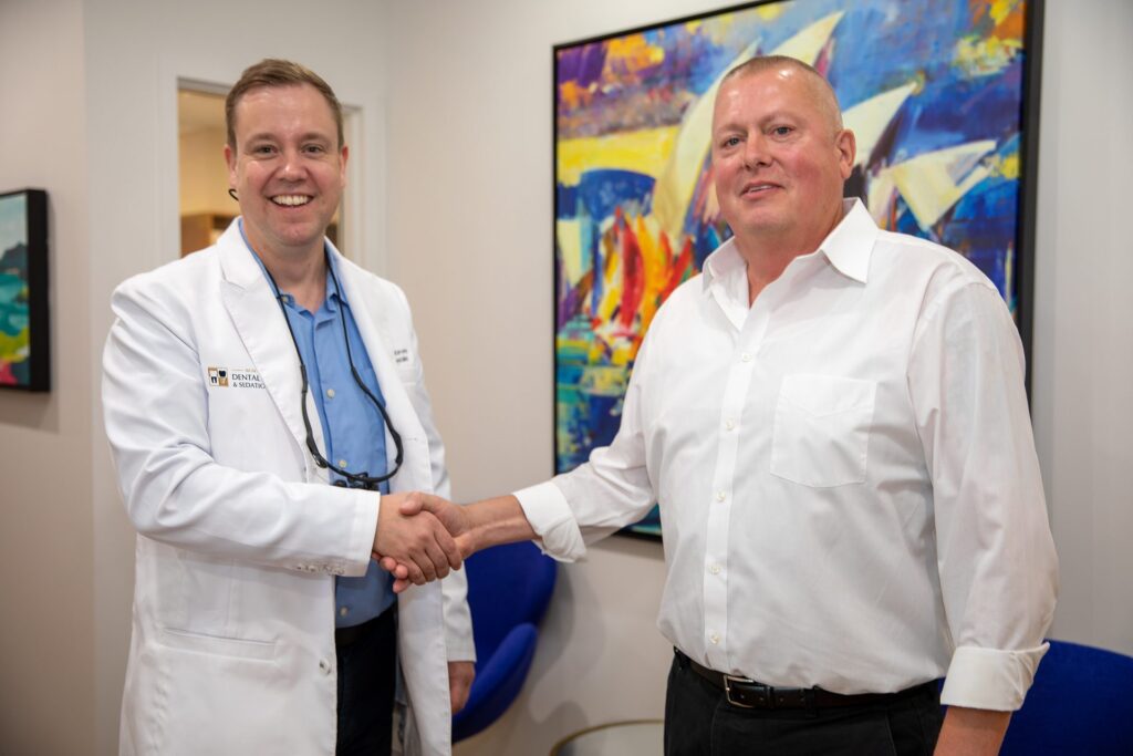 Dr. Niels Oestervemb shaking hands with a happy upper All-on-4 dental implant patient