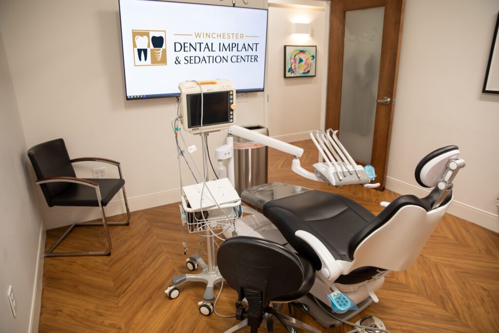 IV sedation treatment room with a vital-signs monitor and dental chair at Winchester Dental Implant & Sedation Center