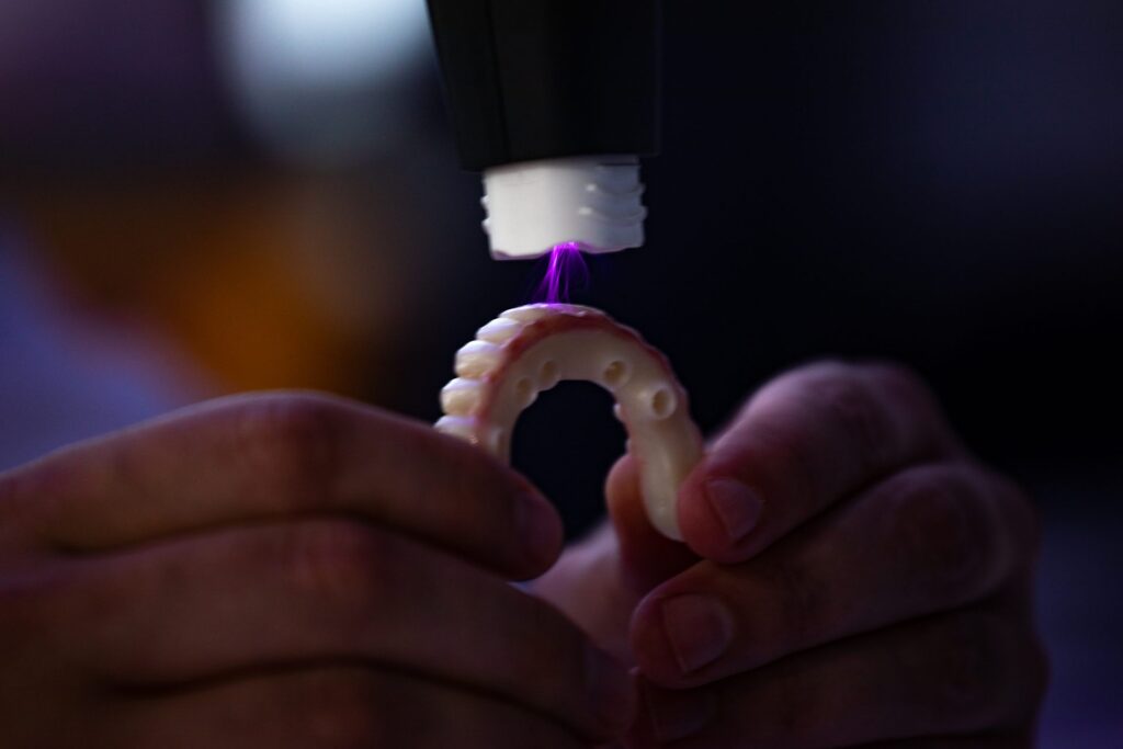 Close-up of a 3D-printed full-arch provisional prosthesis being light-cured in the in-house lab