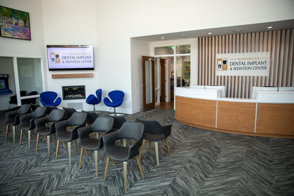 Lobby and waiting room of Winchester Dental Implant & Sedation Center with the reception desk, fireplace and seating